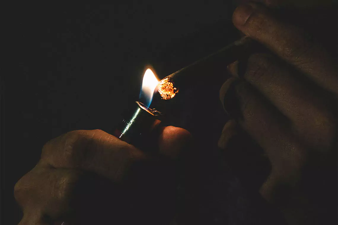 Person igniting a joint with a lighter.