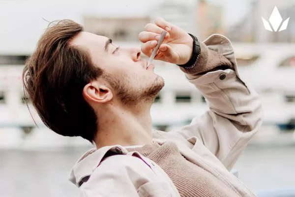 Man smoking outside with his head tilted back.