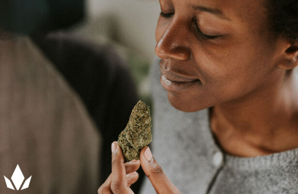 Woman joyfully holding a cannabis strain, eyes closed, smiling in blissful satisfaction