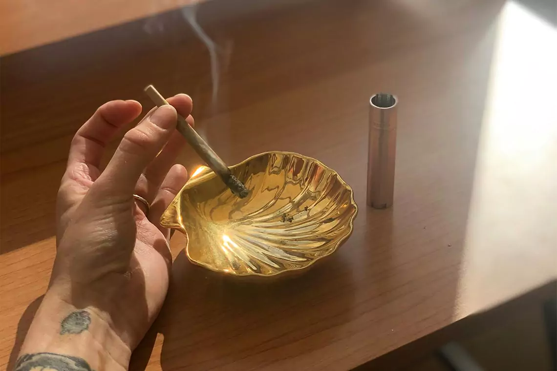 Smoking a joint over an ash tray.