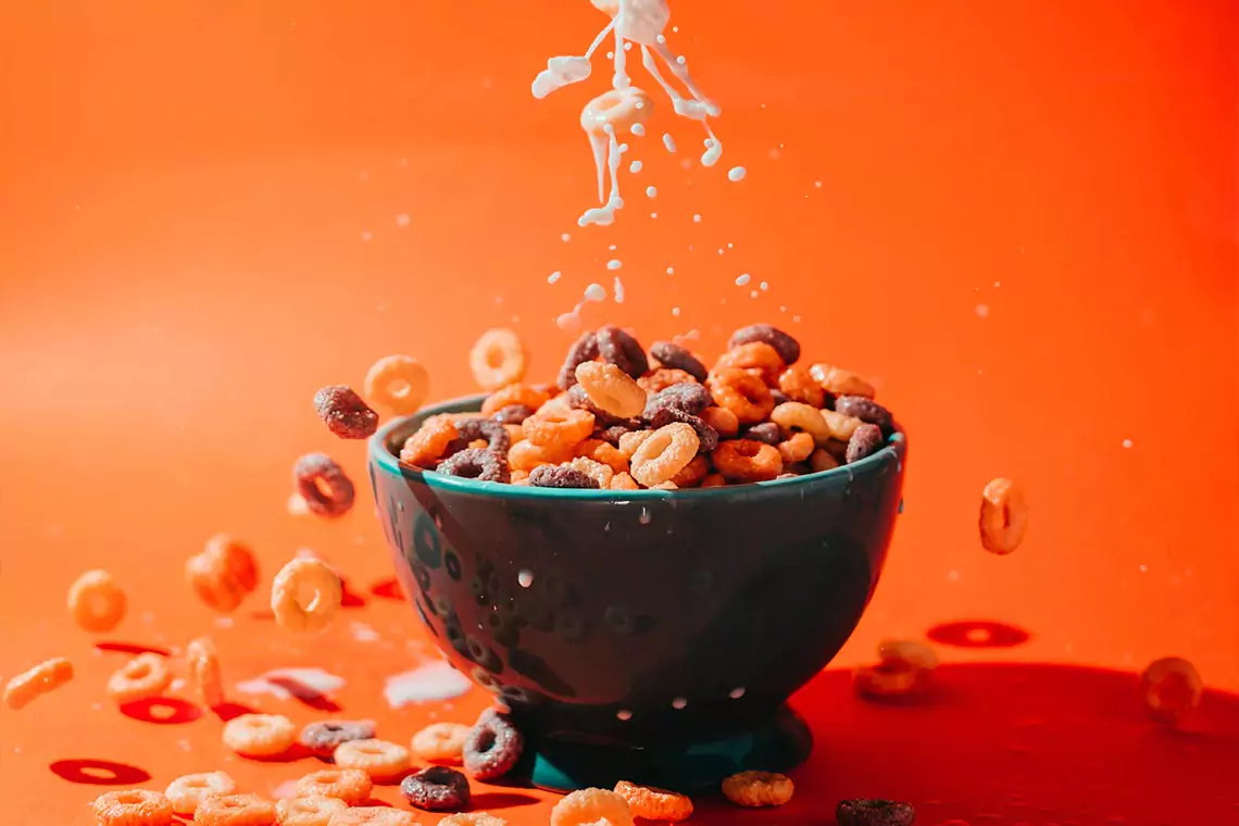 Milk being poured into bowl of cereal.