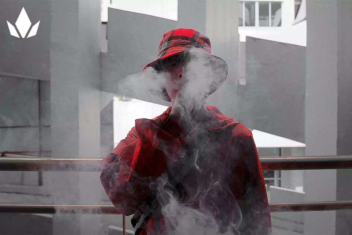 Person smoking in a red shirt and hat.