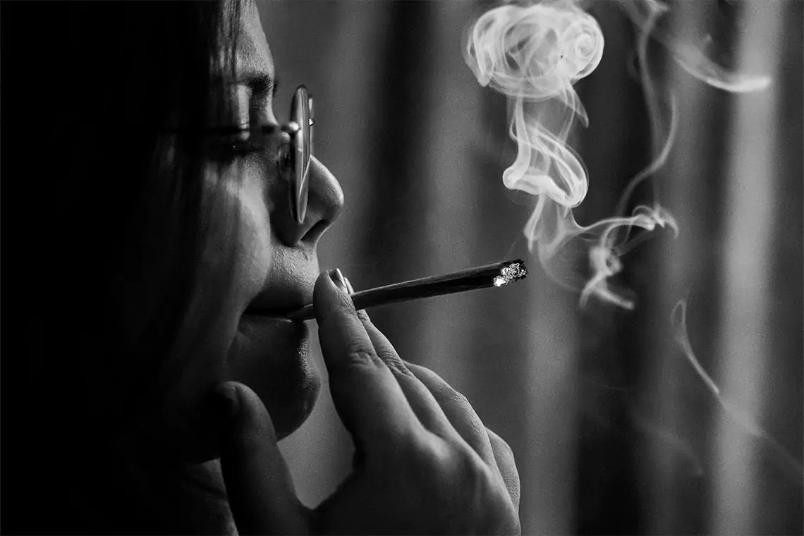 Black and white picture of a woman smoking a joint.