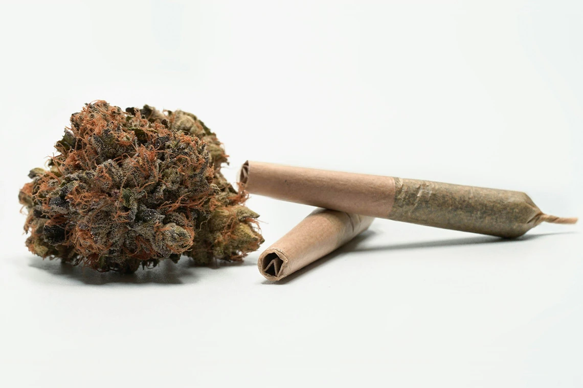 Cannabis Flower Next to Two Prerolled Cannabis Joints