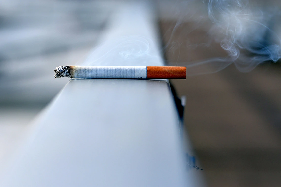 Lit Cigarette Resting on a Ledge