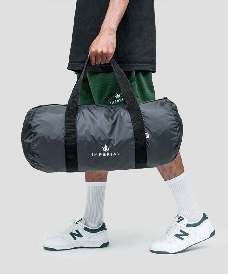 Imperial Merch essentials signature duffle bag in charcoal and black held by model