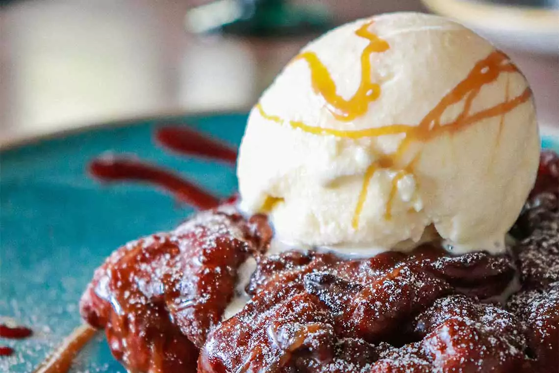 Scoop of ice cream over an apple fritter donut.