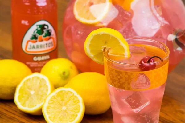 Guava Jarritos in a glass with a lemon on the rim.